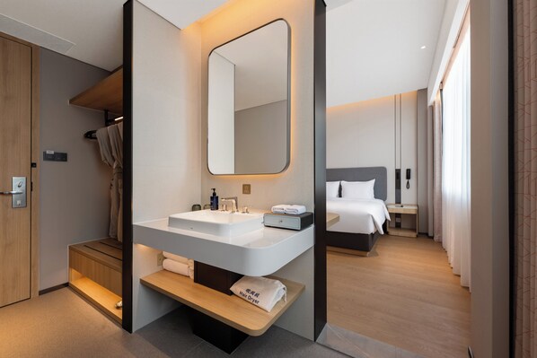 A modern hotel room with a large bathroom sink, a mirror, a bedside table, a bed, and a small wooden bench. - Holiday Inn Express Chengdu Huanhuaxi by IHG (Chengdu)