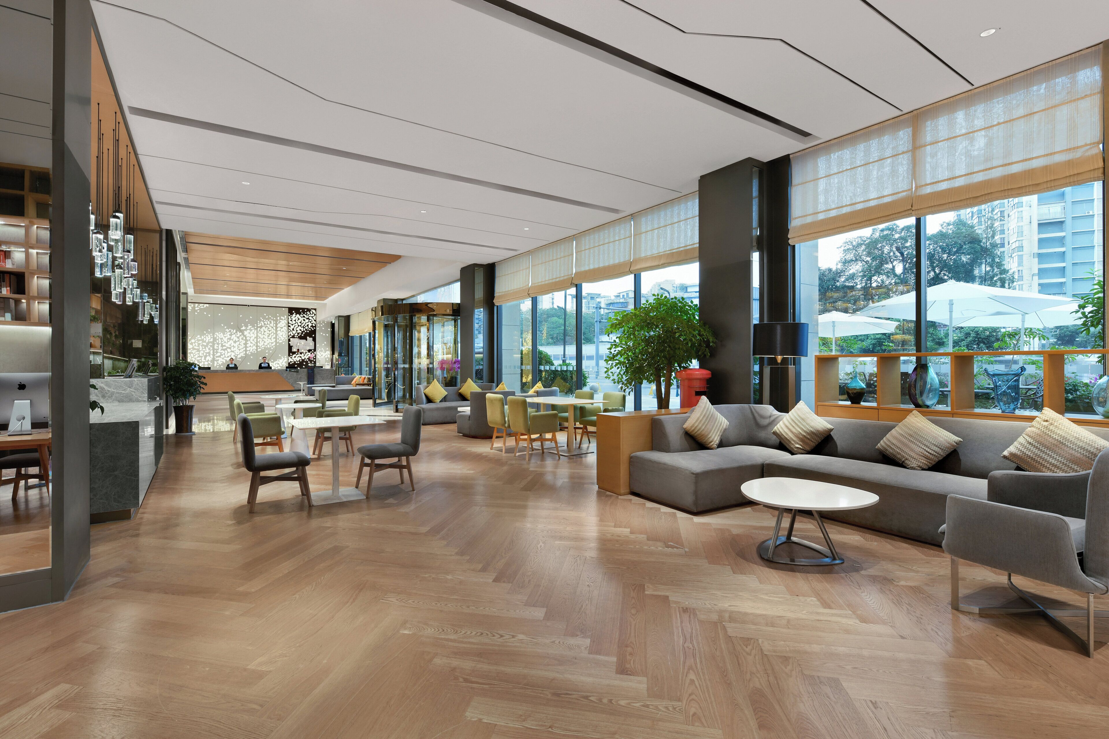 Eine großzügige Lobby mit modernem Design, mit verschiedenen Sitzbereichen, einem Empfangstisch und großen Fenstern, die einen Blick auf die Stadt ermöglichen.