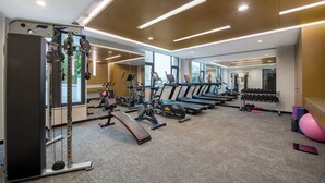 Une salle de sport moderne équipée de divers appareils, notamment des tapis de course, des appareils de musculation et des haltères.