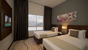 A hotel room with two beds, a large window with a mountain view, a painting on the wall, and a pool table on the left.