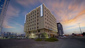 A multi-story hotel with a flat facade, multiple windows, and a large vertical sign.
