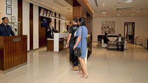 A reception area with a wooden reception desk, a TV screen, and a seating area with a couch and a coffee table.