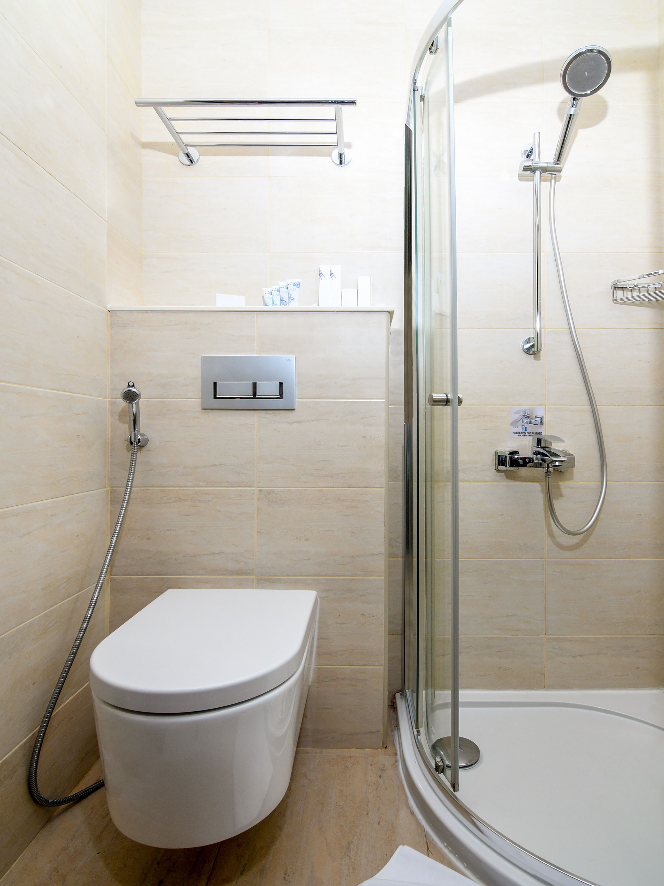 Une salle de bain comprenant des toilettes, une douche avec une porte en verre et un porte-serviettes.