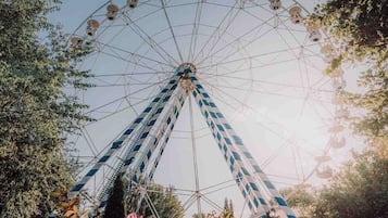 A Ferris wheel with a blue and white striped pattern, surrounded by trees and foliage.