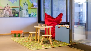 Un espace de jeux pour enfants avec un château, une église et une chaise rouge.