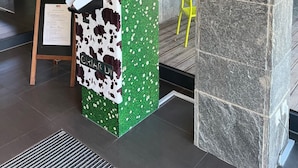 Un comptoir d’enregistrement au design orné de motifs de vaches, une enseigne indiquant « ENREGISTREMENT » et une plaque indiquant une note de 4 étoiles.