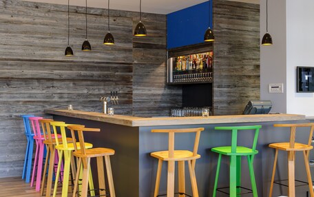 A bar area with wooden bar stools, a bar counter, and hanging pendant lights.