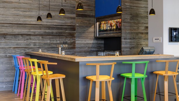 Un espace bar avec des tabourets de bar en bois, un comptoir et des lampes suspendues.