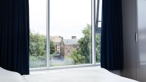 A bedroom with a large window, a bed, and a wardrobe. - Destiny Student Holyrood - Campus Accommodation (Edinburgh)