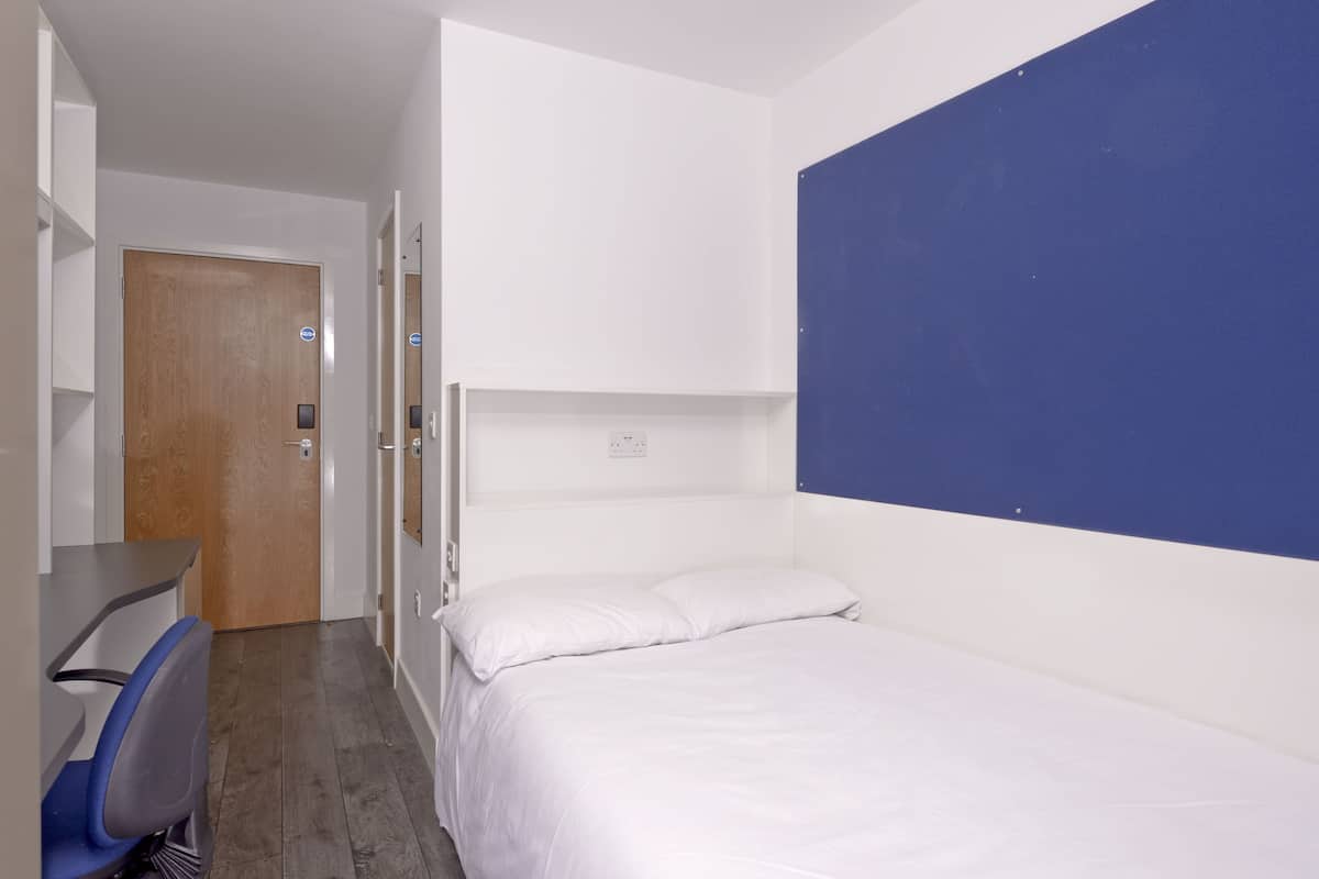 A hotel room with a bed, a desk, and a chair.