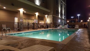 An indoor swimming pool with lounge chairs and a lifeguard station.
