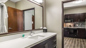 A bathroom with a large mirror, a sink, and a dark wooden vanity. - MainStay Suites Midland (Midland)