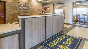 A MainStay Suites reception area with a stone wall, a reception desk, and a view of the lobby. - MainStay Suites Midland (Midland)
