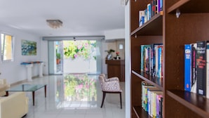 A modern living room with a sofa, a glass coffee table, a chair, and a bookshelf filled with books. - Xidas Garden  (Mylopotamos)