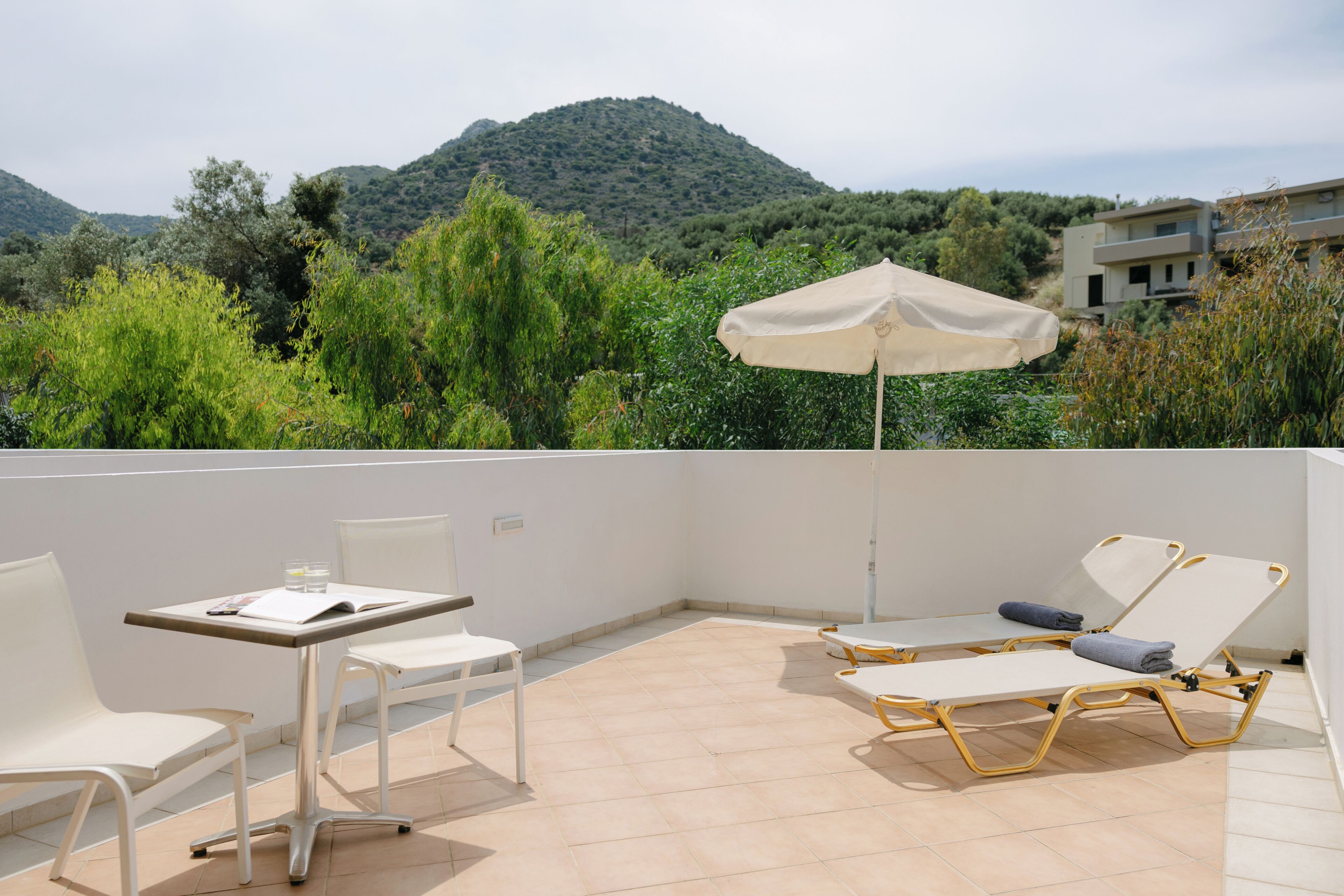 A terrace with a table and chairs, an umbrella, and a view of a mountain.