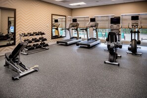 A gym with treadmills, weight machines, and dumbbells.