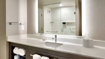 A modern bathroom with a large mirror, a sink, and a towel rack.