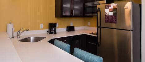 A modern kitchen with a stainless steel refrigerator, a coffee maker, and a dishwasher.