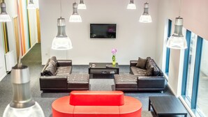 Ein stilvoller Lounge-Bereich mit Ledersofas, einem roten Akzent und Pendelleuchten.