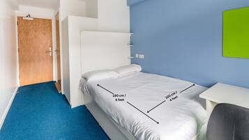 Quarto de hotel compacto com uma cama individual medindo 190 centímetros de comprimento e 120 centímetros de largura.