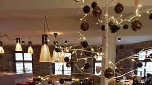 Une pièce chaleureuse avec un mur en briques rustiques, une table à manger dressée et un traîneau décoratif illuminé.