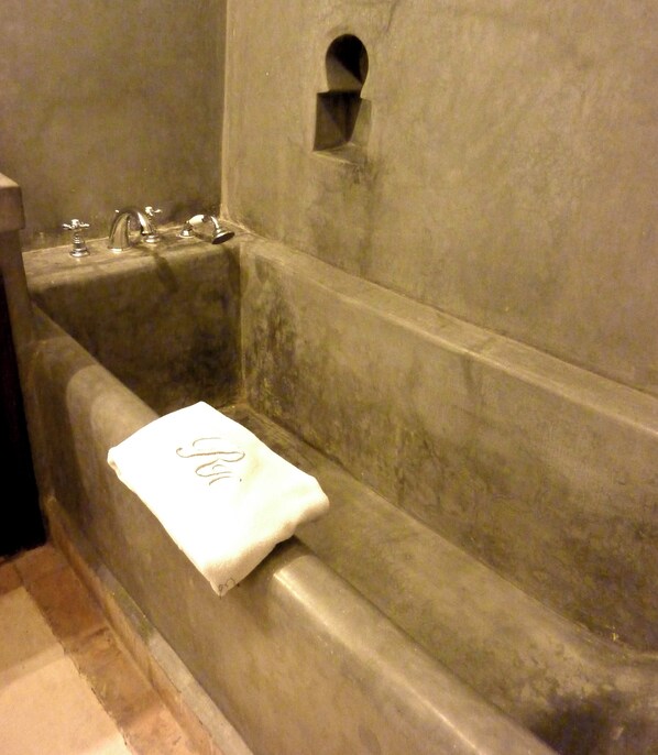 Une baignoire avec une serviette, une petite fenêtre et un robinet.