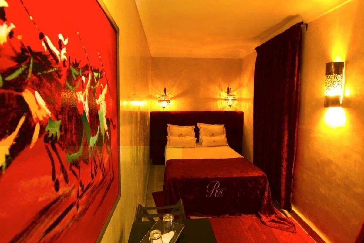 Une chambre d’hôtel avec un lit, des lampes de chevet, un tableau au mur et une petite table avec un plateau.