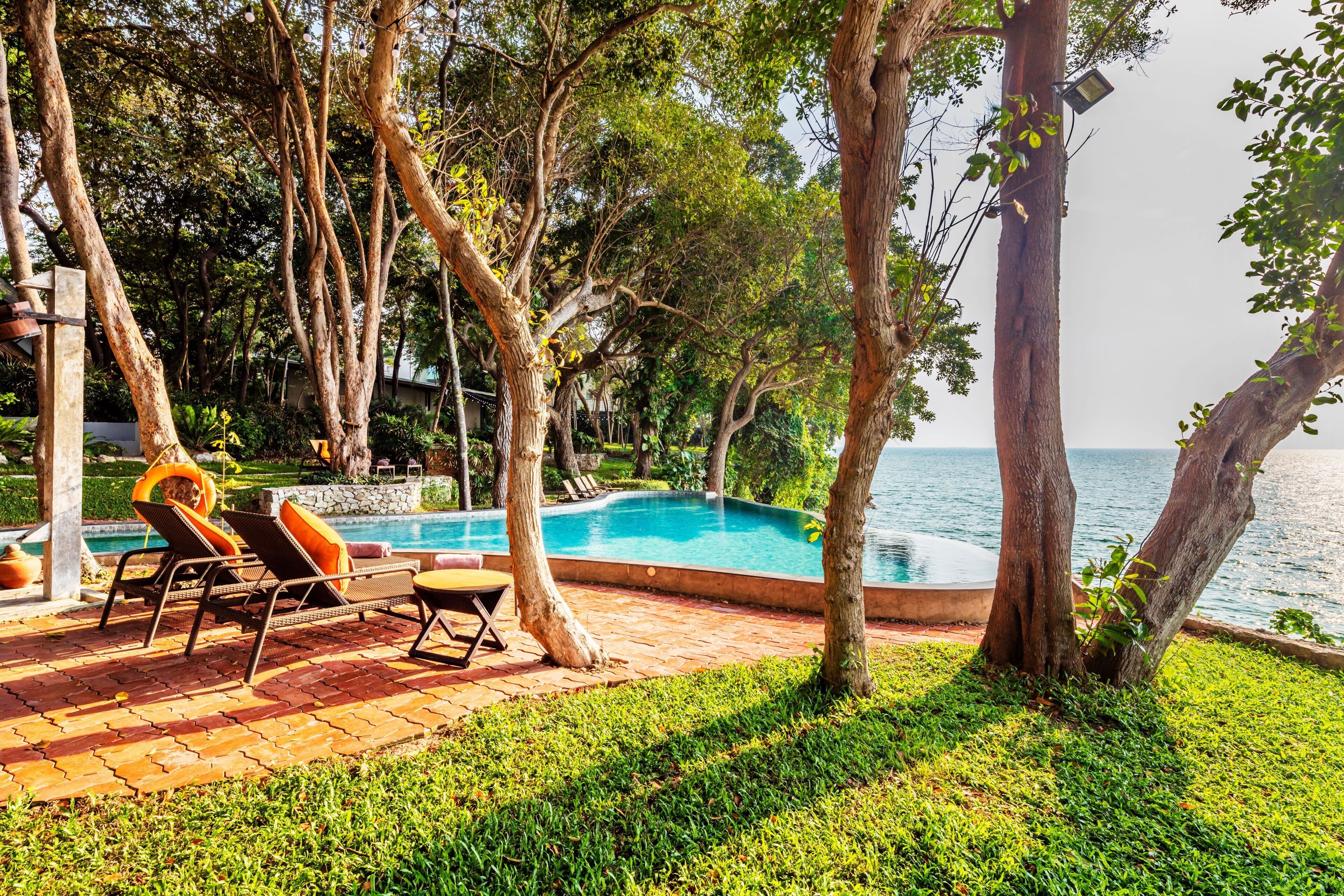 A poolside area with lounge chairs and a view of the sea.