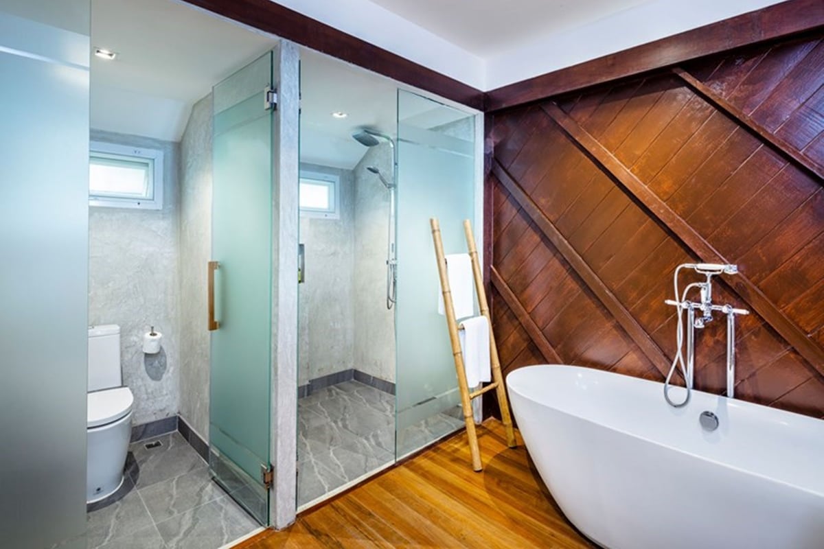 A modern bathroom with a glass-enclosed shower, a freestanding bathtub, and a wooden floor.