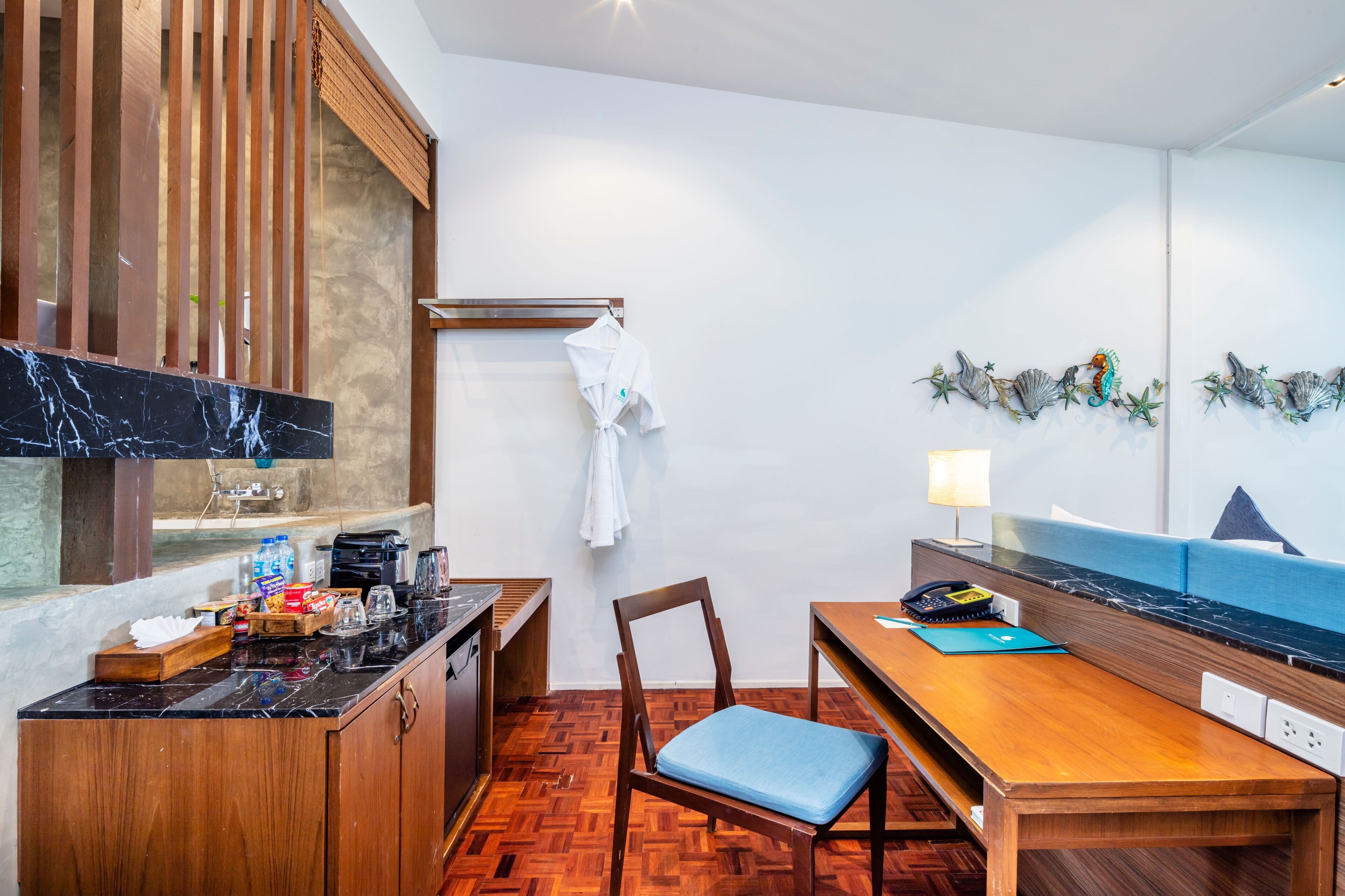 Eine kleine Küche mit Holzarbeitsplatte, Spüle und Herd. Es gibt einen Holztisch mit einem Stuhl und eine Couch an der Wand.