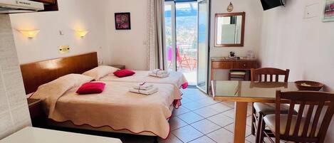 Habitación de hotel con cama, escritorio, silla, televisión y vistas al exterior.