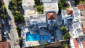An aerial view of a residential area with a swimming pool, multiple buildings, and a street. - KTM Sunny Villas (Poros)