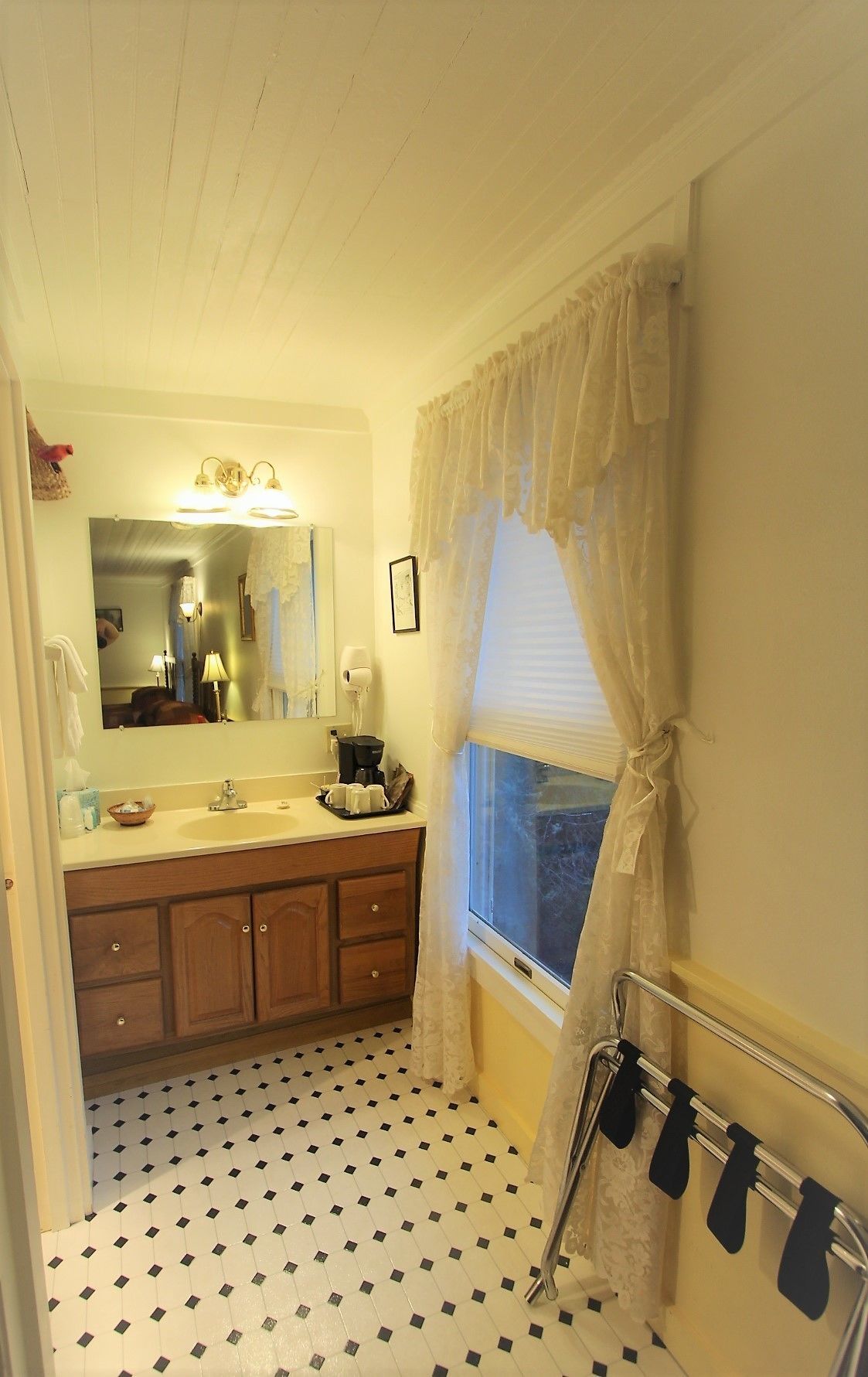A bathroom with a sink, mirror, and window with curtains.