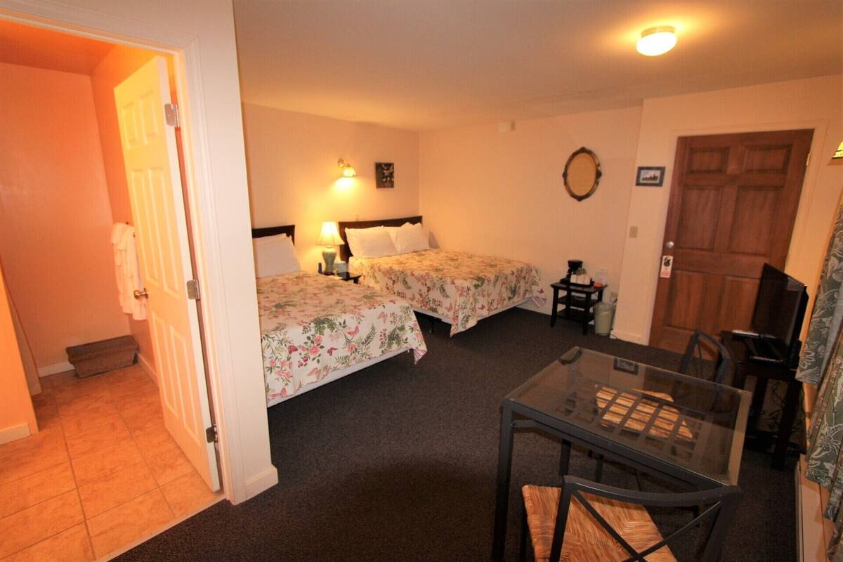 Ein Hotelzimmer mit zwei Betten, einem kleinen Tisch und einem Fernseher.