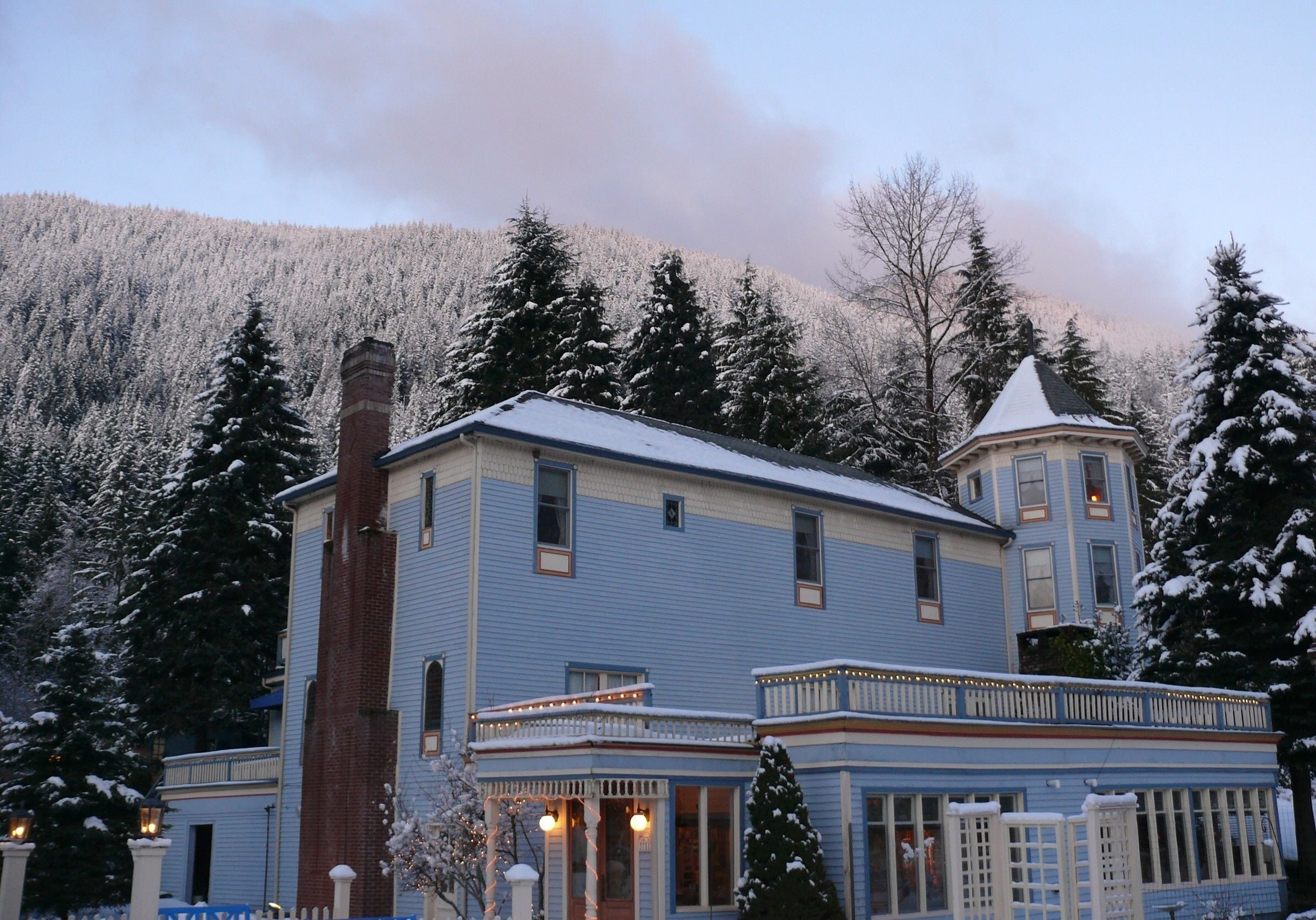 A two-story building with a blue exterior and a brick chimney.