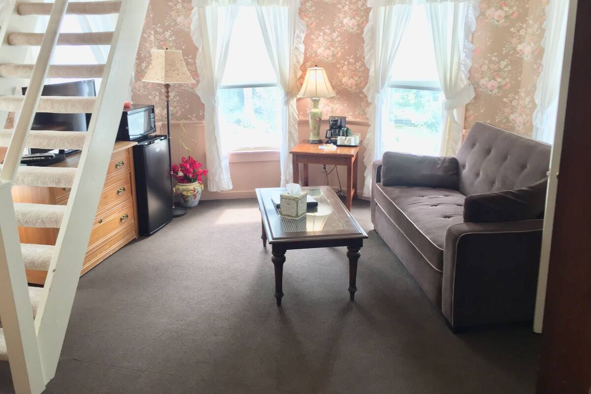 Ein gemütliches Wohnzimmer mit einer Couch, einem Couchtisch und einer Treppe.
