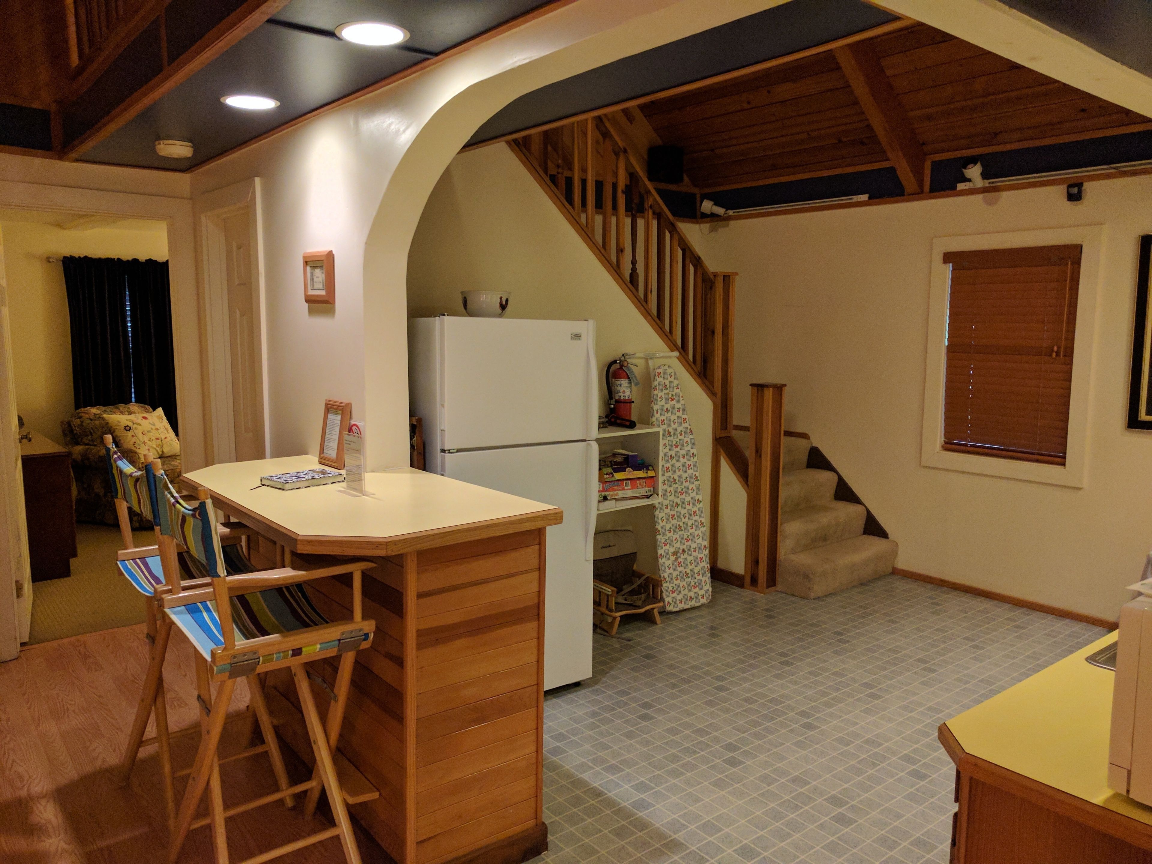 Una cocina compacta con una isla de madera, un refrigerador y una escalera que lleva a un nivel superior.