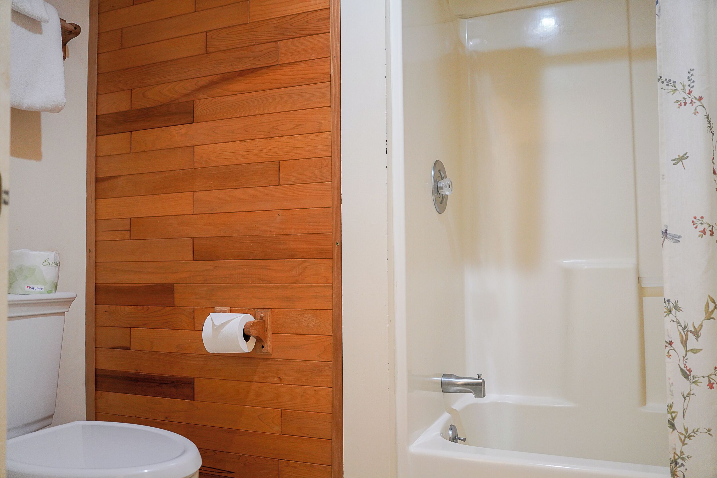 Un baño con pared de madera, un inodoro y una bañera.