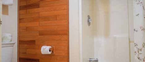Un baño con pared de madera, un inodoro y una bañera.