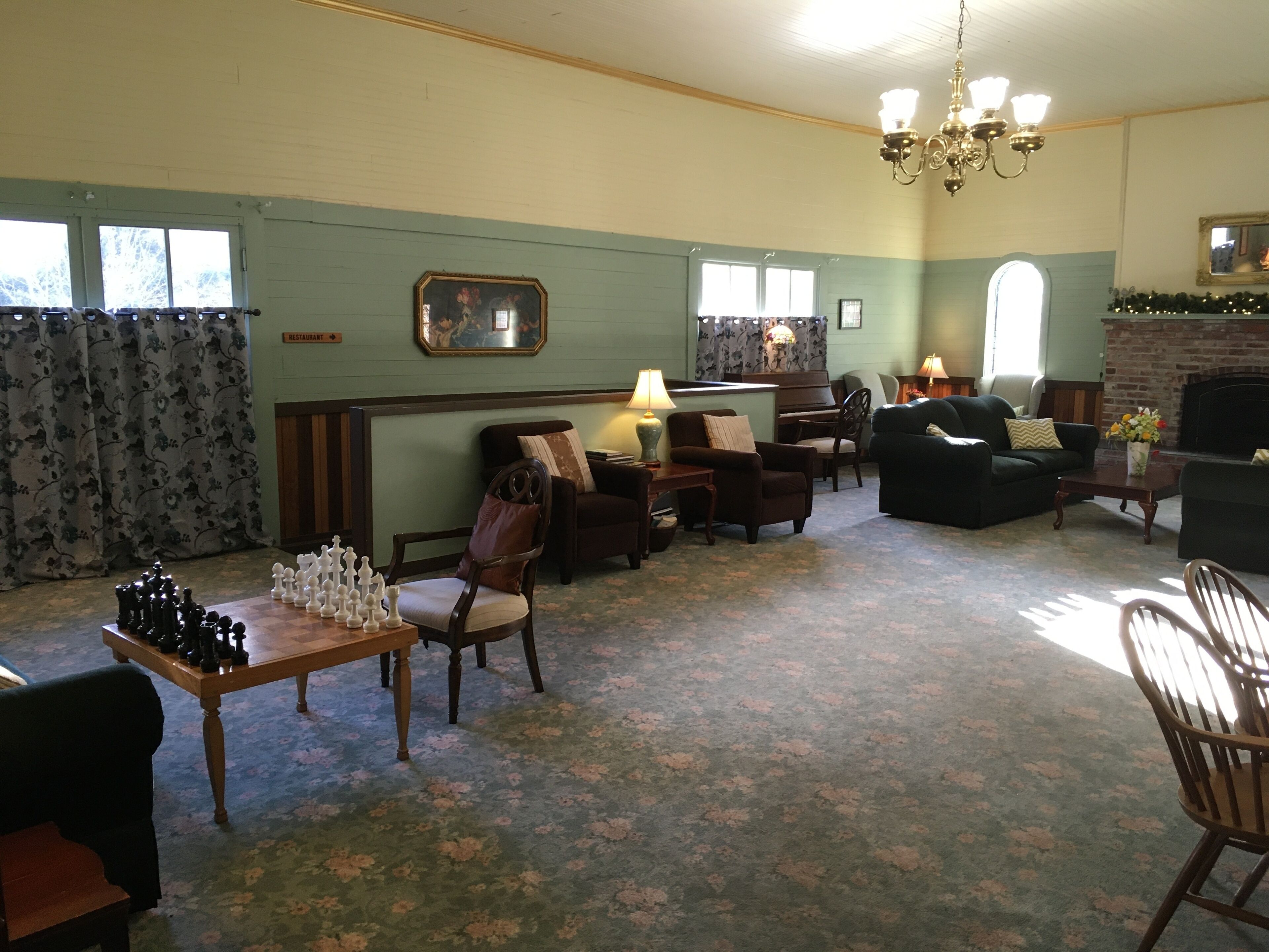 A cozy living room with a piano, a fireplace, and a chessboard.