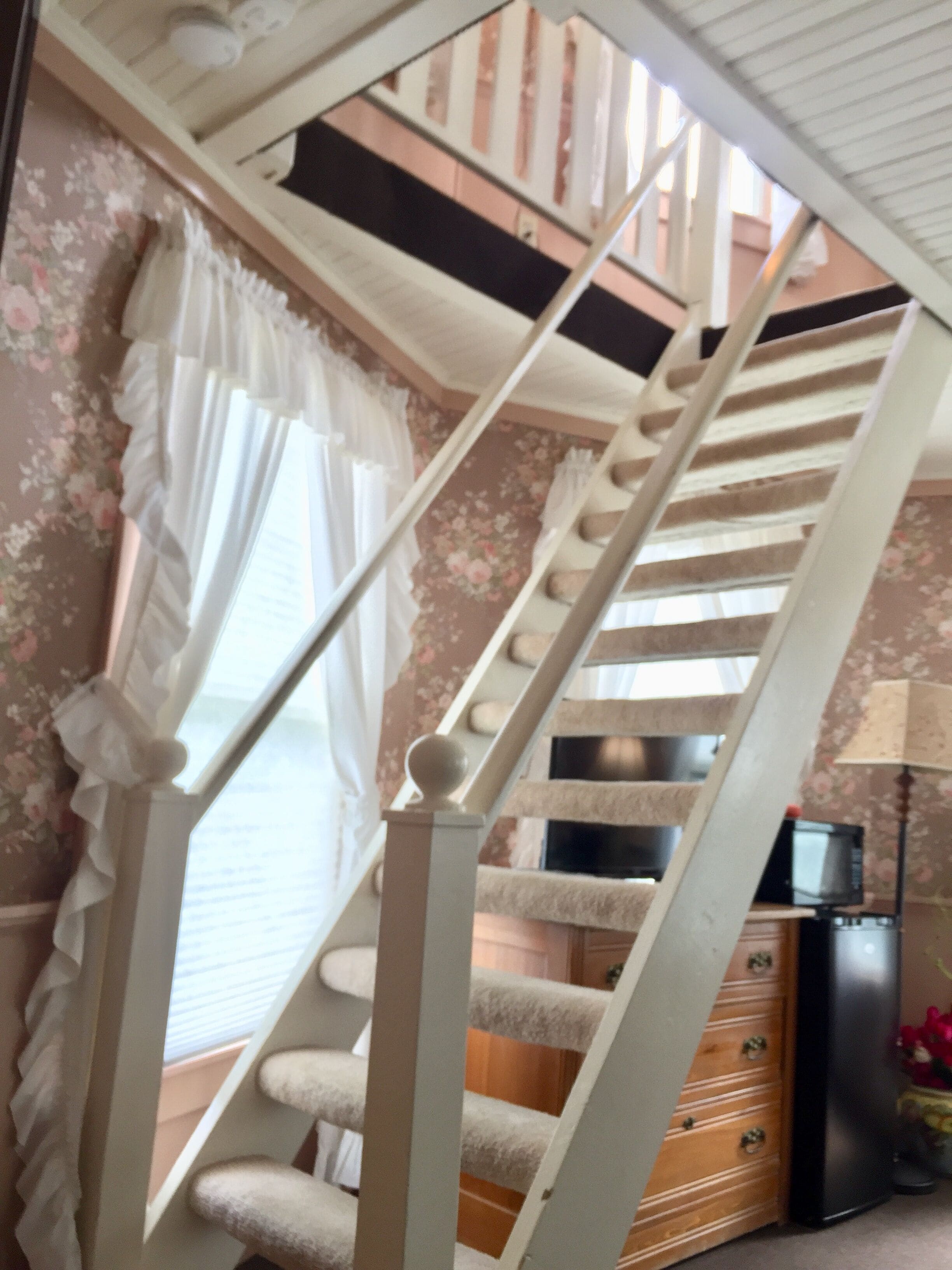 A staircase with a wooden finish and a cushioned landing area.