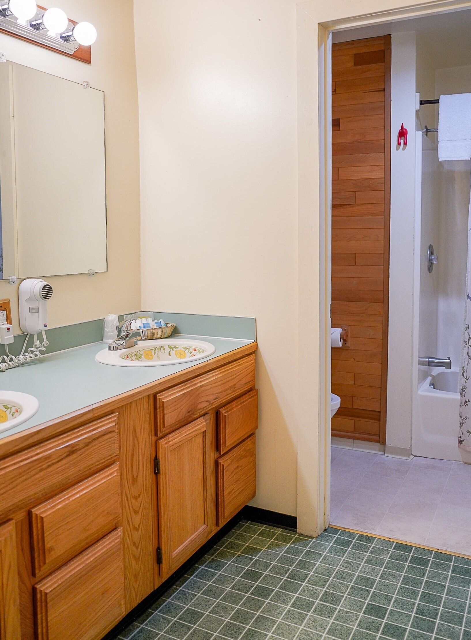 A bathroom with wooden cabinets, a sink with a mirror, and a shower area.