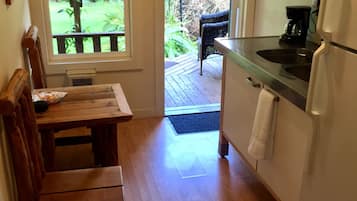 A kitchen with wooden flooring, a dining table, and a refrigerator.
