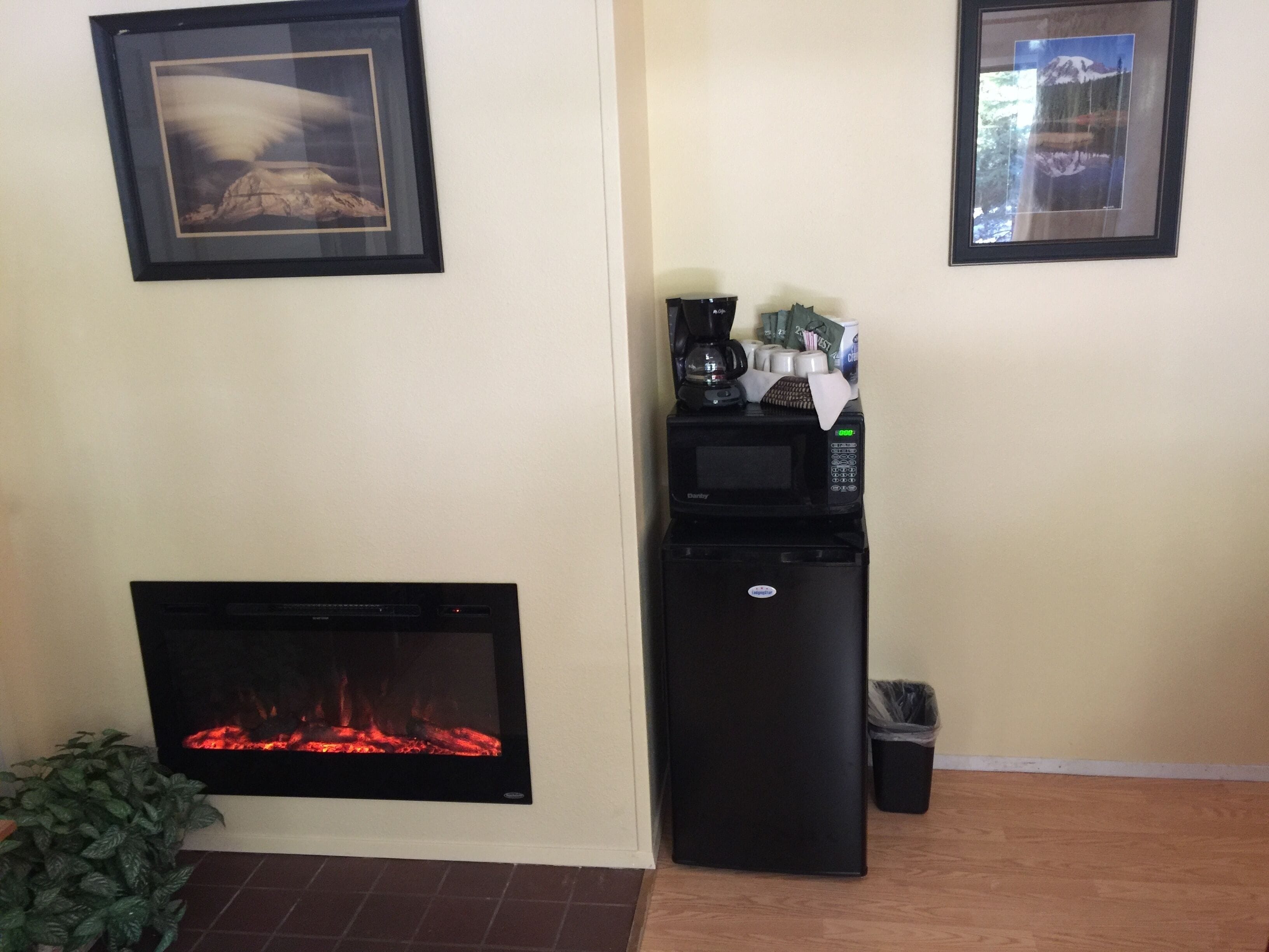 Una sala de estar con chimenea, una cafetera y cuadros en la pared.