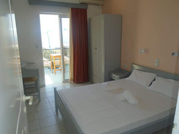 Una habitación de hotel con cama, armario, una mesita y una silla.