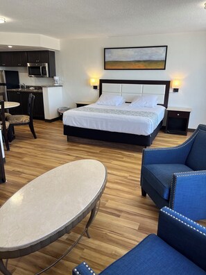 A hotel room with a bed, a dining table, a sofa, and a kitchen area. - Flamingo Inn Beachfront (Daytona Beach Shores)