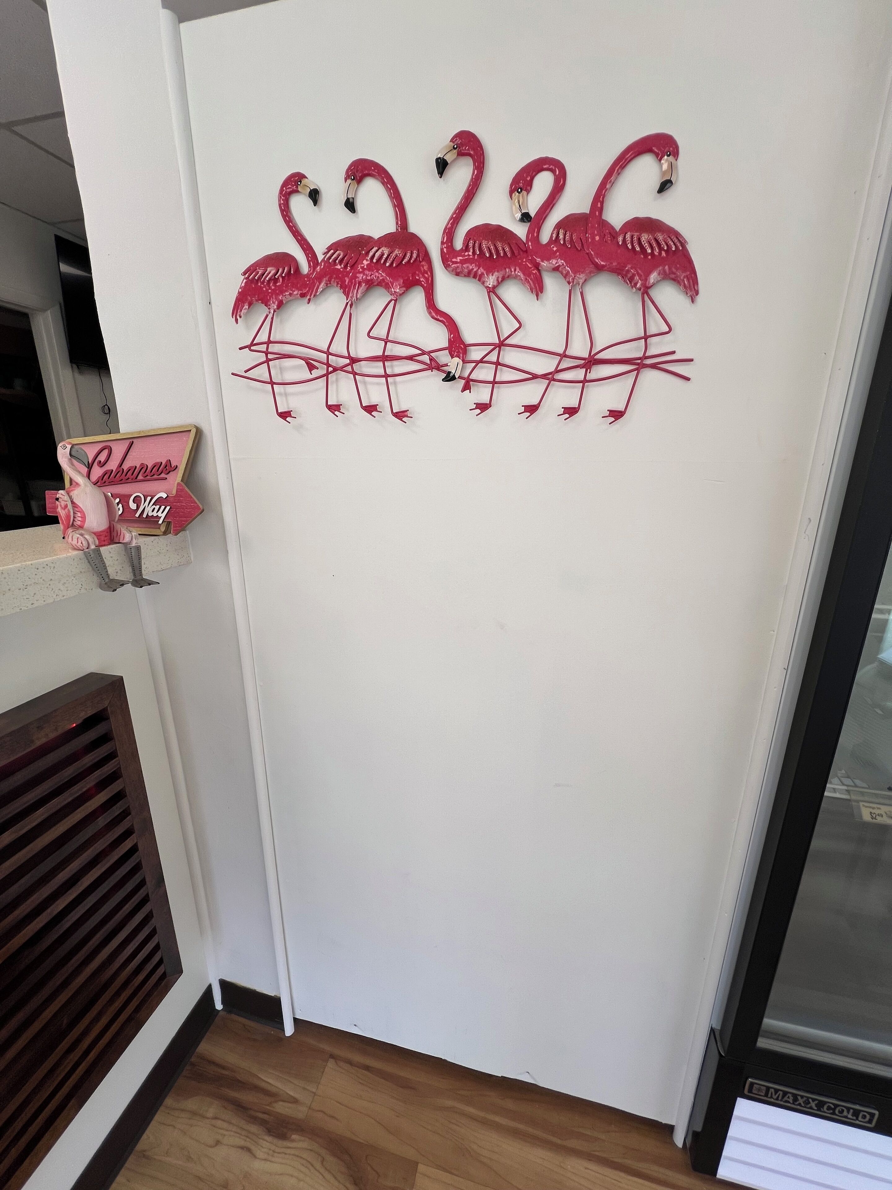 Una pared con un letrero decorativo de flamenco y un letrero que dice 'Cabanas is Way'.