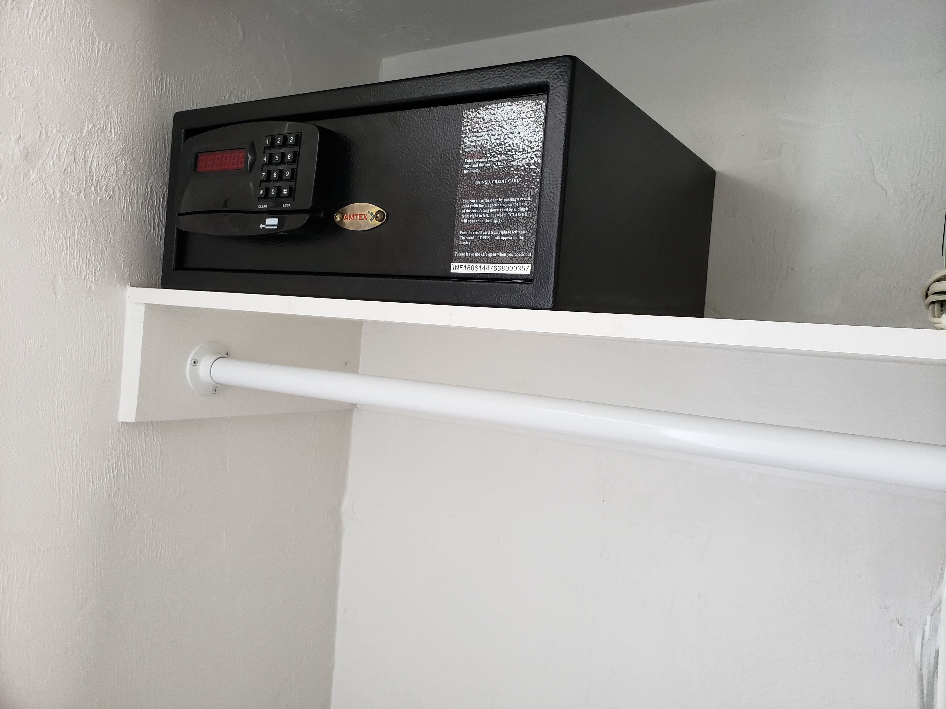 A security keypad with a display and a lock mechanism on a white wall.