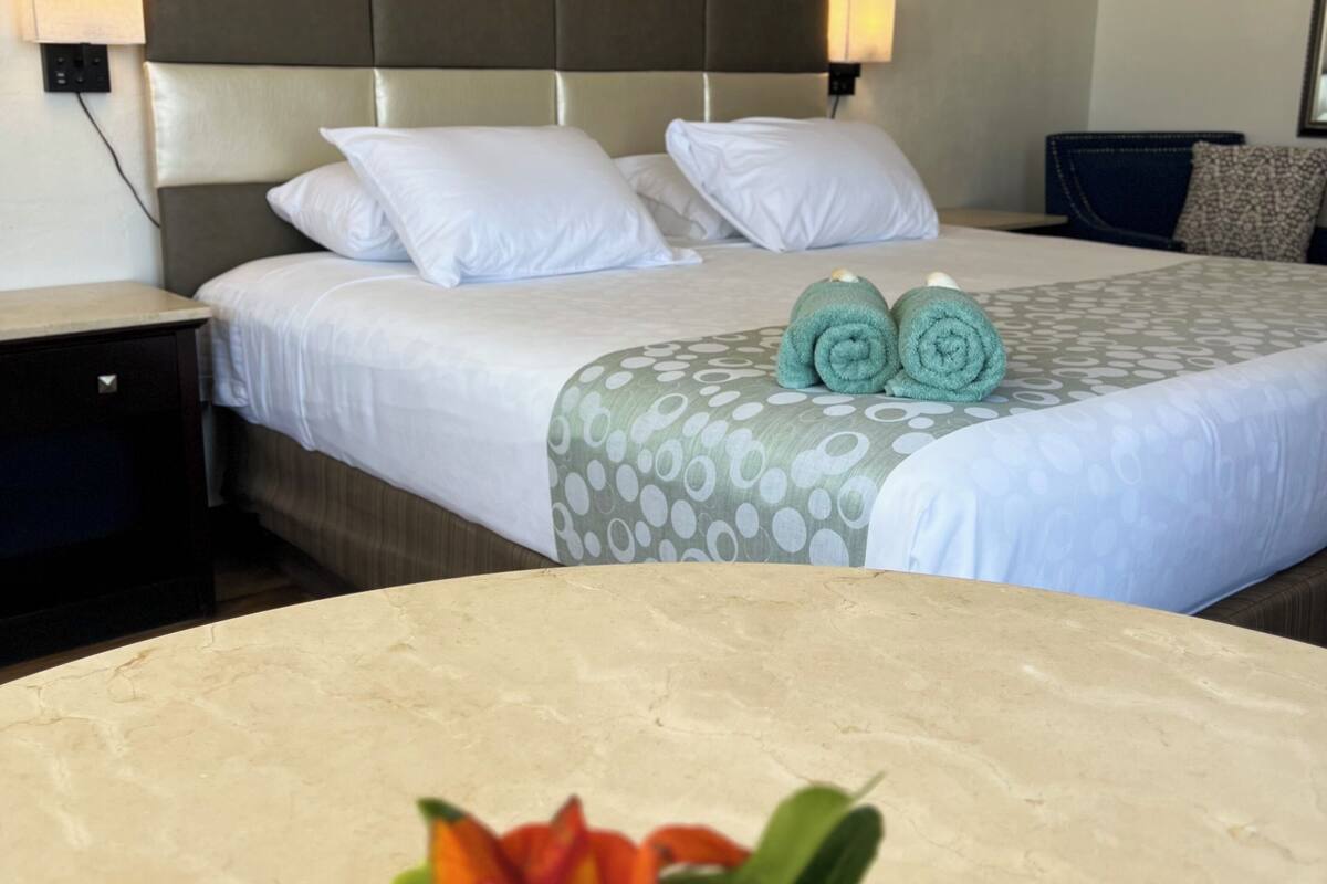 Ein Hotelzimmer mit Bett, Nachttisch und einem an der Wand hängenden Bild.