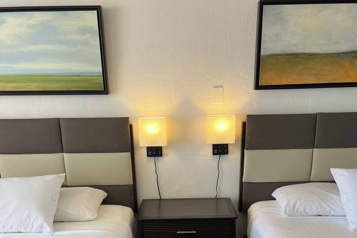 Ein Hotelzimmer mit zwei Betten, einem Nachttisch und Wandlampen.